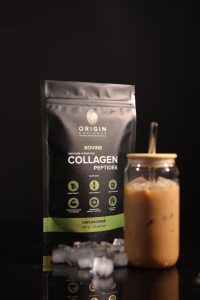 Front-facing collagen pouch standing upright with iced coffee and ice on black background
